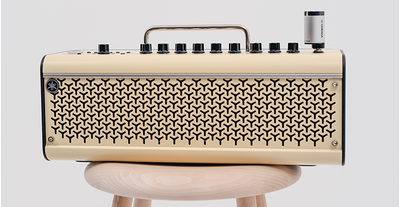 The THR30II Wireless guitar amp that the YW10T is plugged into its input jack is on the wooden stool, on a gray background.