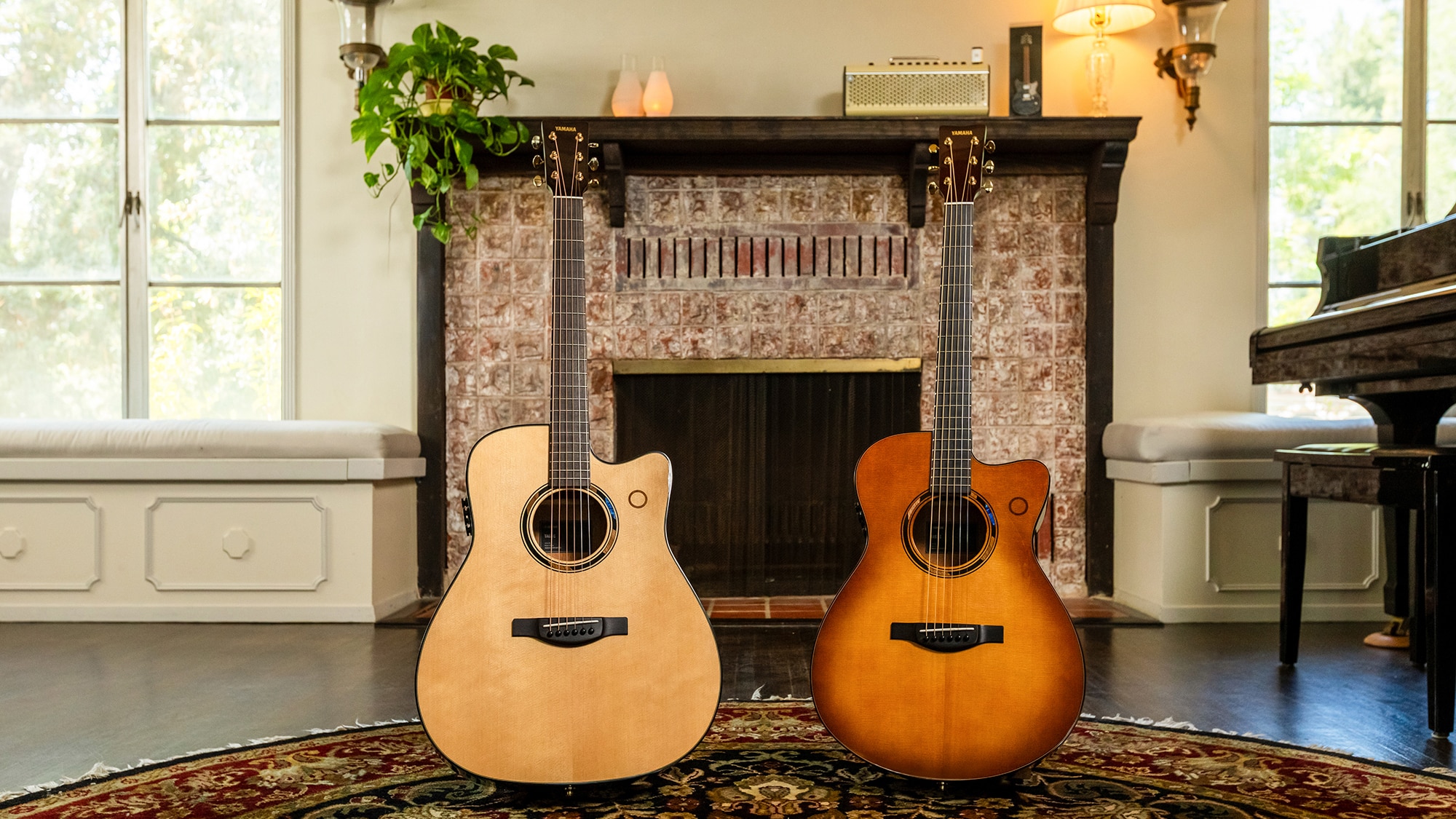 Two acoustic guitars standing in front of a fireplace indoors.