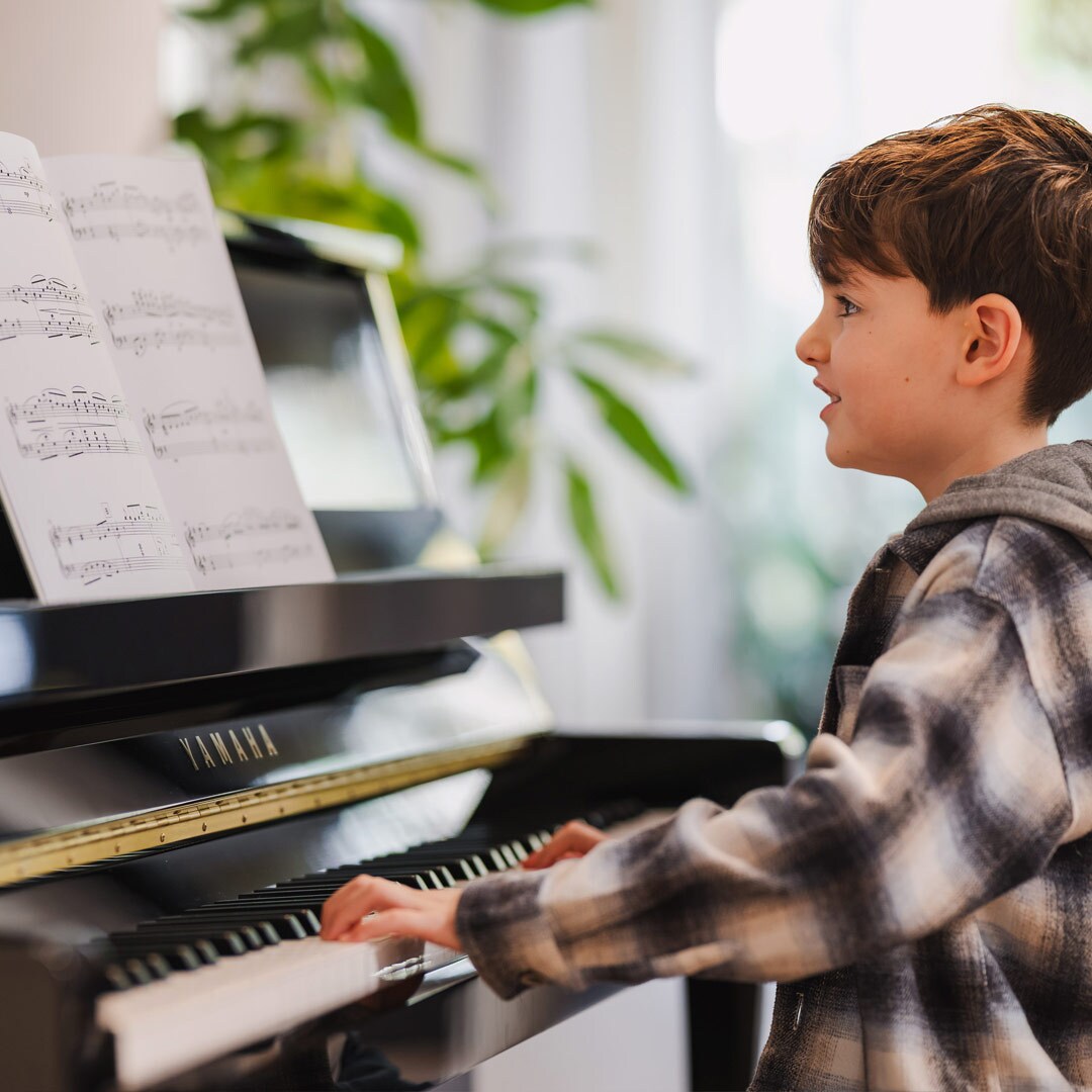 Un niño disfruta tocando el piano vertical de la serie B