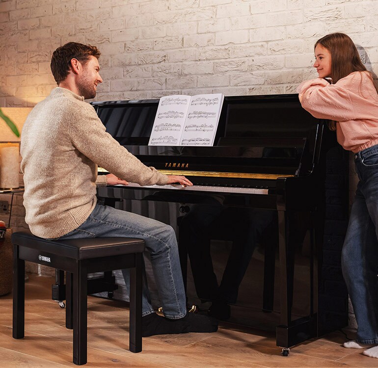 A mother and daugter enjoy playing the upright piano B series