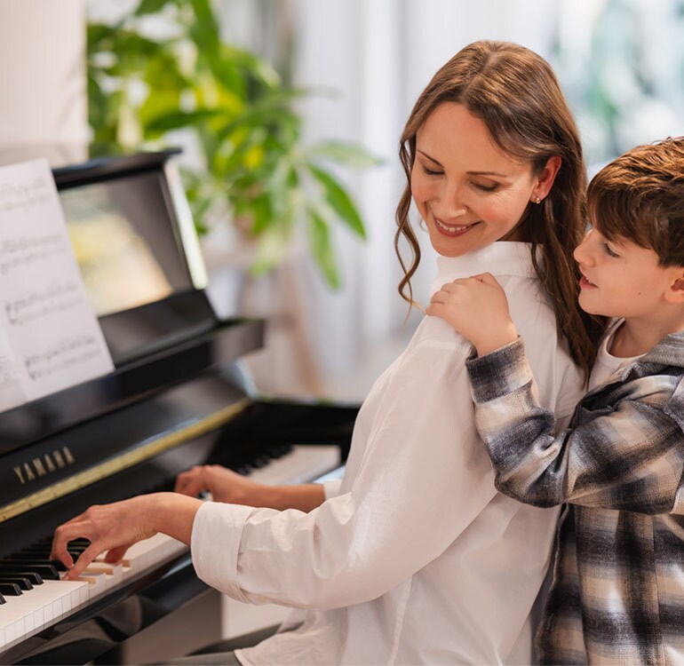 Una madre y su hija disfrutan tocando el piano vertical serie B