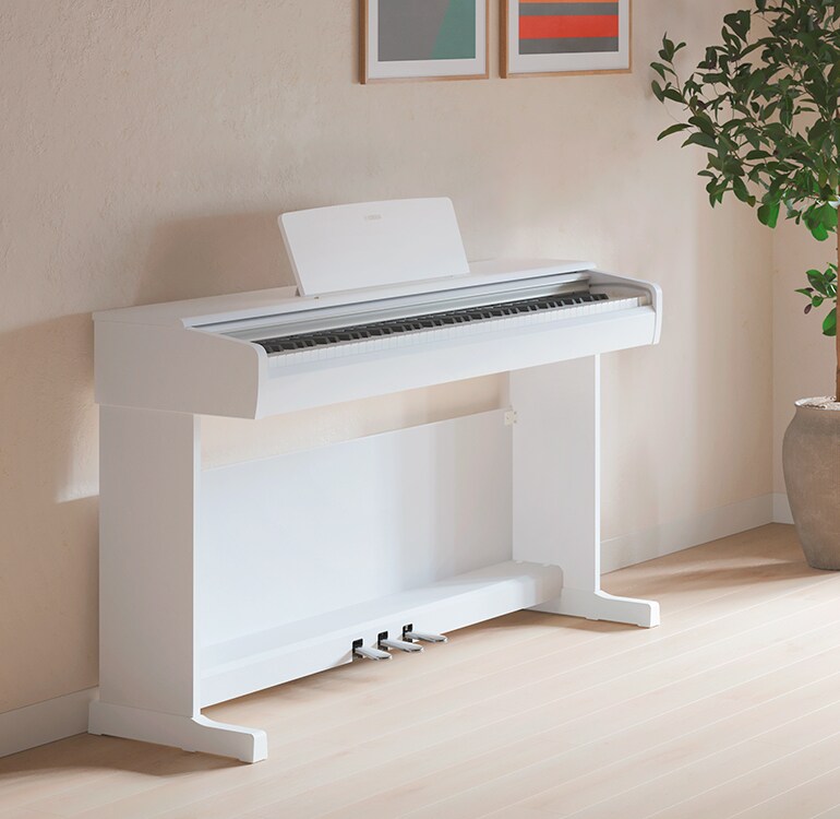 Una sala de estar que cuenta con un piano ARIUS color blanco con plantas de interior y un sofá, armoniosamente integrado con la decoración