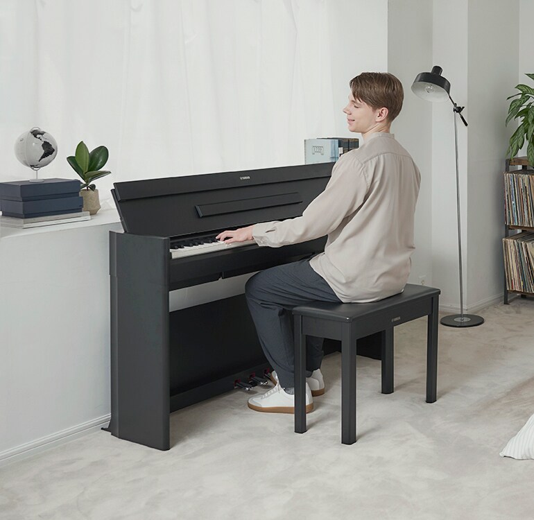 Un hombre tocando un piano ARIUS en una habitación en un ambiente relajado
