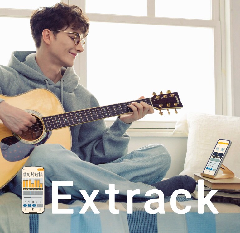 Un hombre disfruta practicando la guitarra sentado en el sofá y tocando junto con la app de práctica musical Extrack
