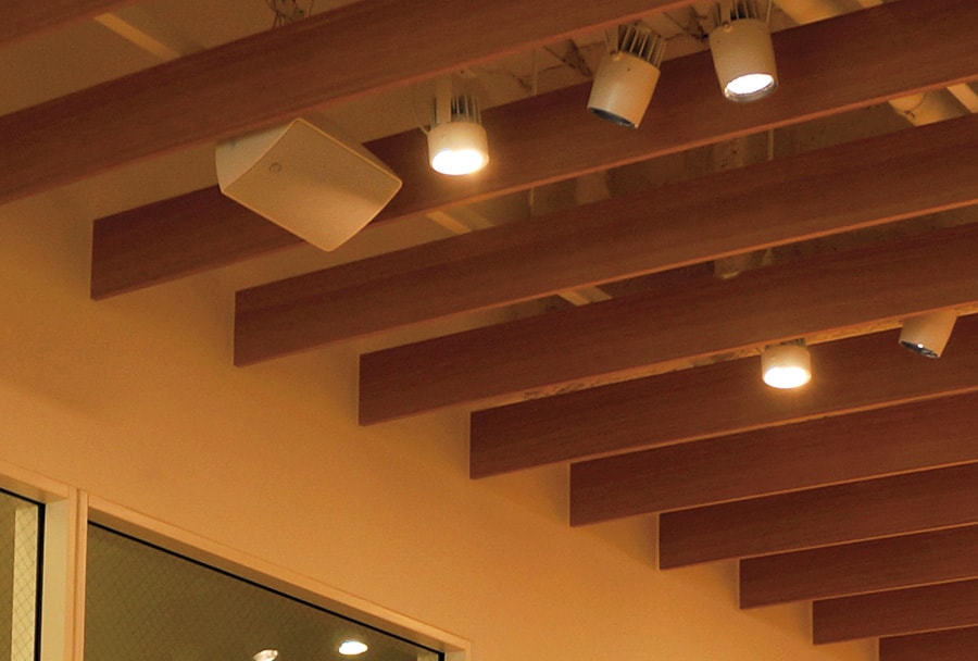 A ceiling-mounted surface-mount speaker providing clear and balanced audio distribution.
